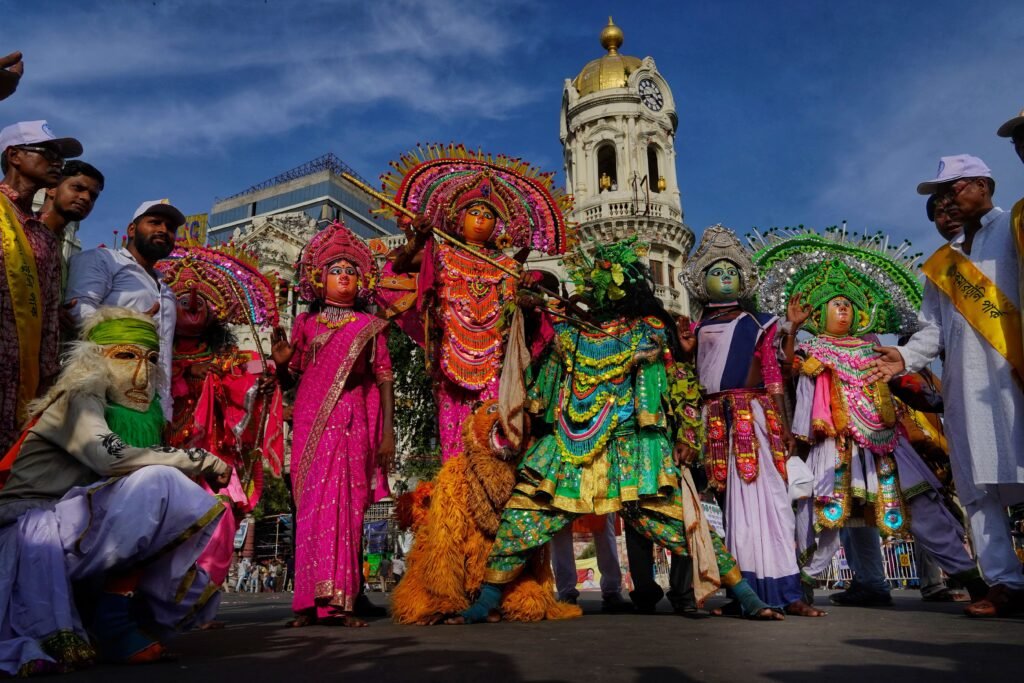 Vibrant festival parade with traditional costumes and performers in central Kolkata, India.