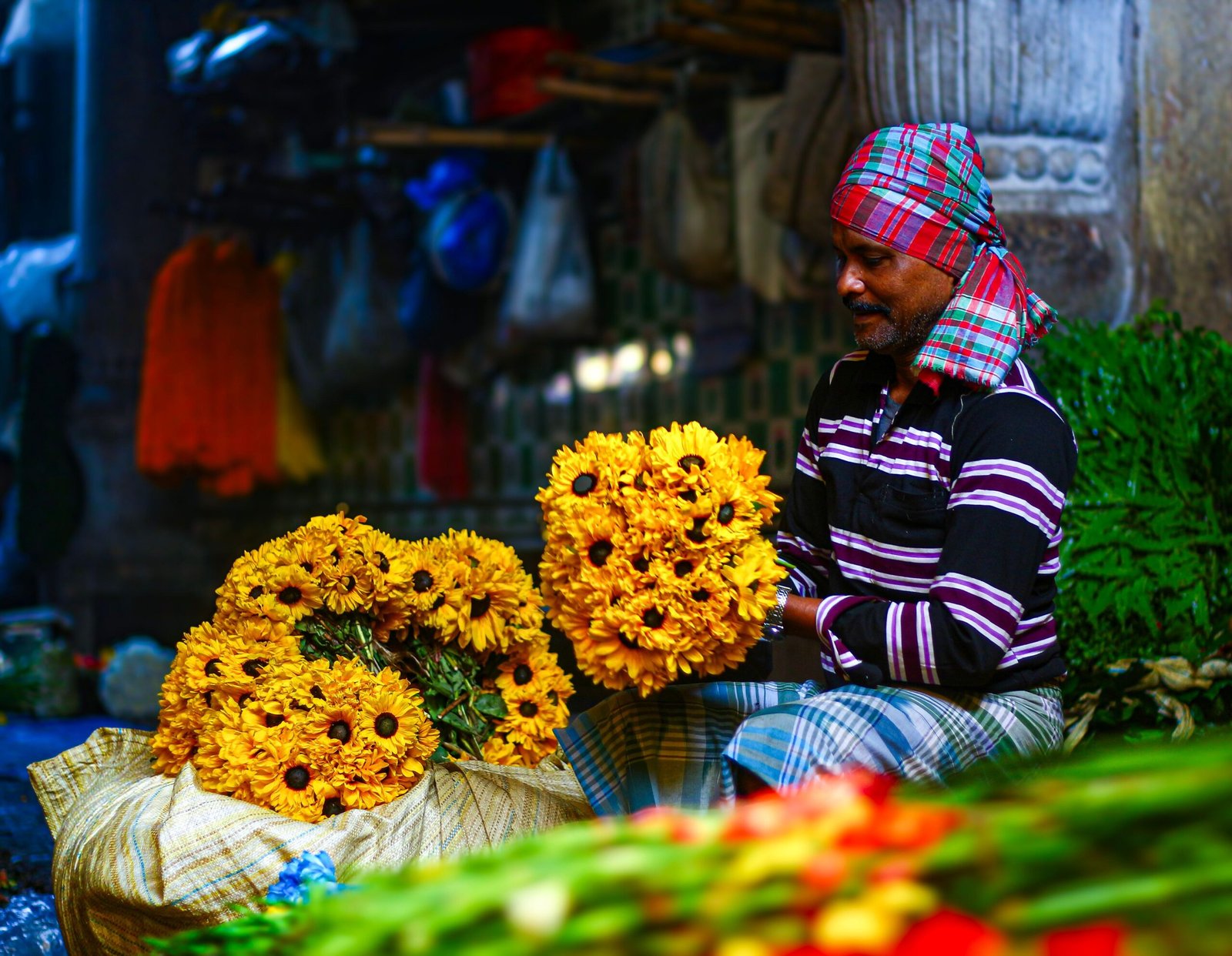A flower vendor arranges vibrant marigolds at a bustling Kolkata market, showcasing local culture and colors.