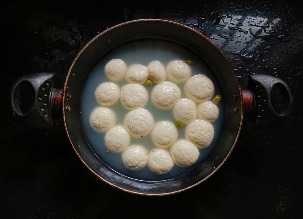 Overhead view of traditional Indian rasgulla sweets cooking in syrup.
